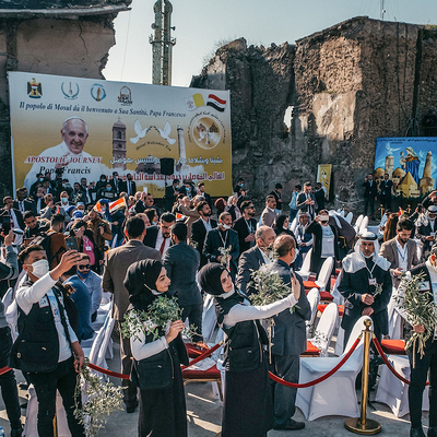 Viele Menschen, darunter junge muslimische Frauen mit Olivenzweigen, warten am Straßenrand auf die Ankunft von Papst Franziskus am 7. März 2021 in Mossul.